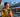 A traveler checks her smartphone and a SIM card on a sunny train platform with the Alps in the background